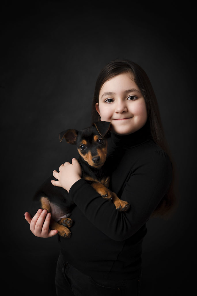 Petite fille avec son chien, pinscher, dans les bras