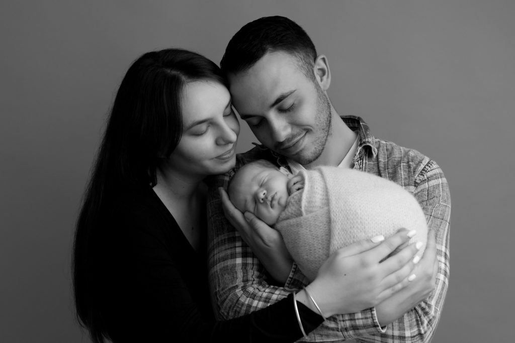 Photo en noir et blanc de jeunes parents avec leur nouveau-né dans les bras