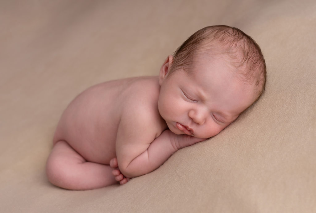 Nouveau-né qui dort sur une couverture beige