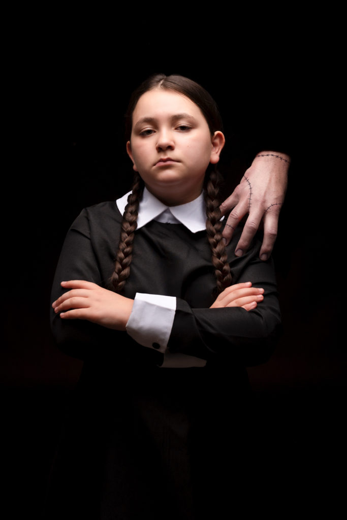 Jeune fille déguisée en Mercredi Addams avec la main, la chose, sur l'épaule