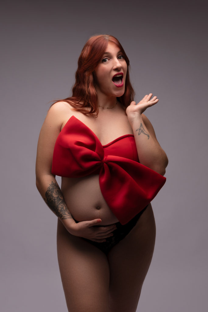 Femme enceinte rousse avec petite brassière rouge avec un noeud